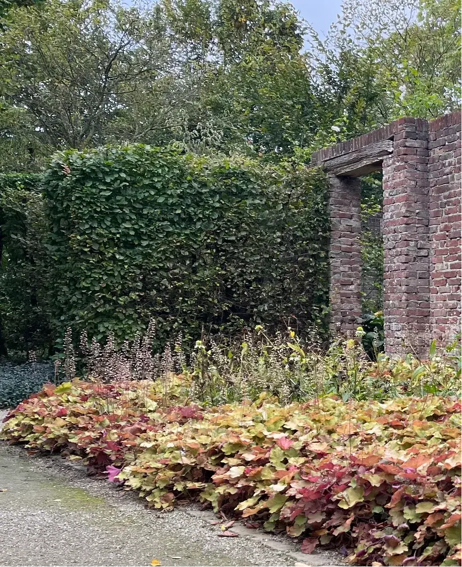 Herfstkleurige border met een gemetselde poort en haag